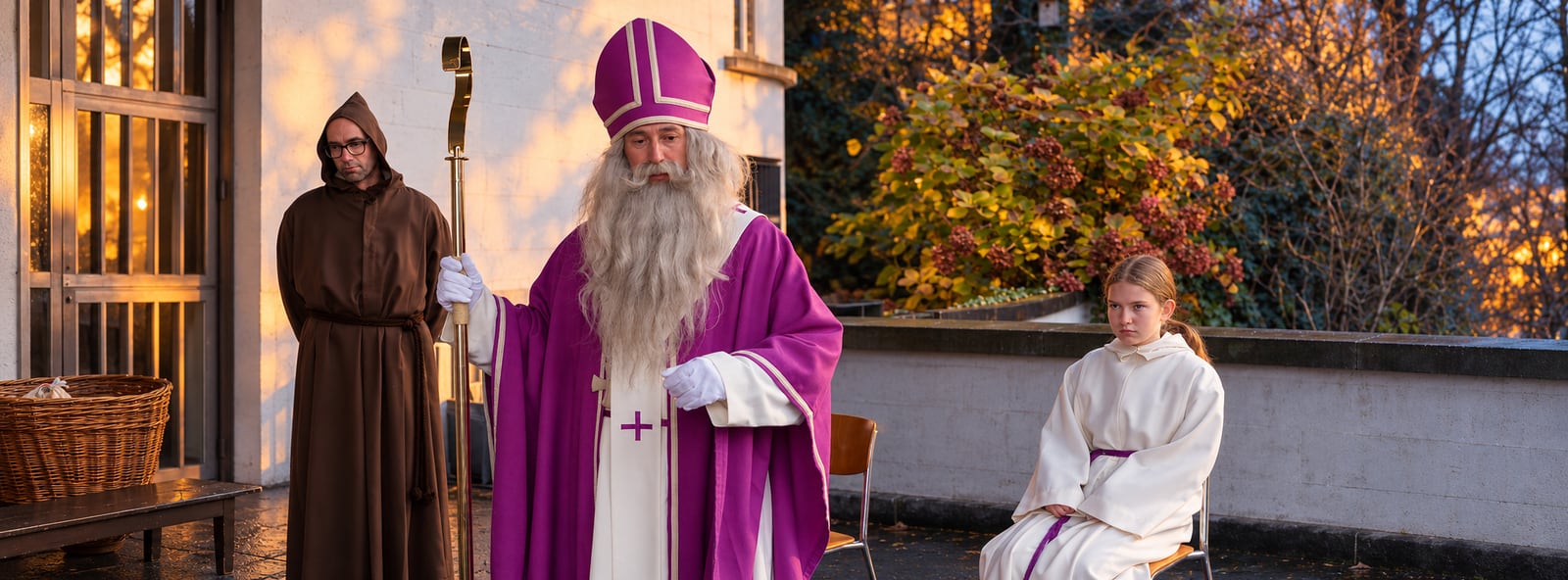 Samichlaus mit Schmutzli und einem Kind vor der Kirche